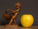 a statue of a boy with a watering can next to an apple