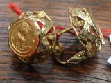 a gold ring with a coin on it on a wooden table