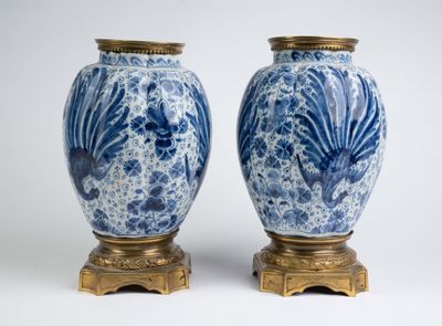 une paire de vases bleus et blancs posés sur un socle doré