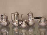 cinq théières en argent posées sur une table en verre