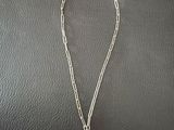 a silver necklace with a pearl on it sitting on top of a black surface