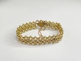 a close up of a gold bracelet on a white surface