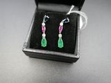 une paire de boucles d'oreilles en émeraude, rubis et diamants, présentée dans un coffret noir