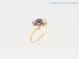 a close up of a gold ring with a sapphire and diamonds