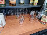 many glasses and bottles on the counter with a pitcher