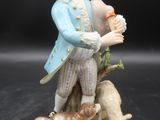 une figurine représentant un homme tenant une bouteille et un chien