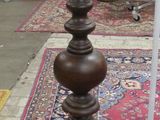a tall wooden candle holder on a rug in a room