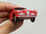 a hand holding a red toy car in front of a white wall