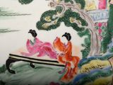 a plate with a painting of a woman and a man sitting on a bench