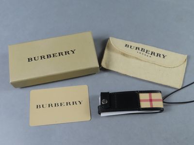 Trois vêtements Burberry sont posés sur une table, à côté d'une boîte