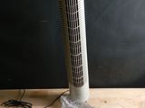 un ventilateur posé sur une table en bois, à côté d'un sac en plastique