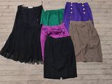 several skirts are lined up on a wooden floor next to a hanger