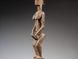 une statue en bois d'un homme avec un chapeau sur la tête