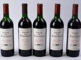 quatre bouteilles de vin rouge sont alignées sur une surface blanche