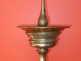 a metal candle holder on a table against a red wall