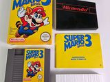 nintendo super mario 3 game cartridges and manuals on a table