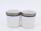 two white cups with blue trims are sitting on a white surface