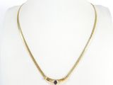 un collier en or orné d'une pierre bleue autour du cou d'un mannequin