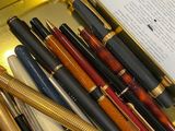 many pens and a book in a box on a table