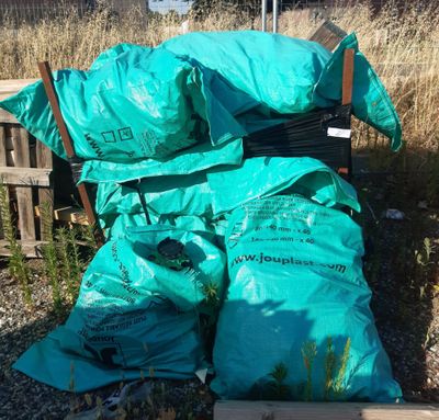 une pile de sacs posée par terre près d'une clôture