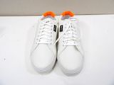 white sneakers with orange laces on top of a white surface