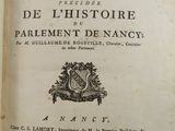 un livre ouvert sur lequel est représenté un blason