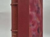 un vieux livre à la couverture rouge posé sur une surface blanche