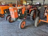 many old tractors parked in a garage together
