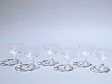 six wine glasses are lined up on a white surface