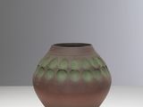 un vase marron et vert posé sur une table blanche