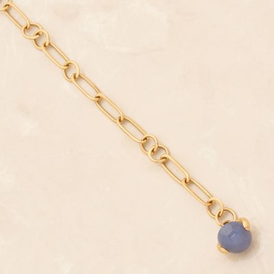 a gold chain bracelet with a blue stone on it