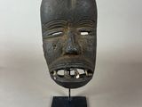 a close up of a wooden mask on a stand on a table