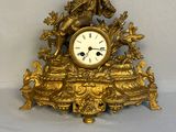 une horloge en or posée sur une table, à côté d'une cuillère