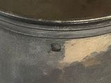 a metal pot with a handle that has a brown substance on it