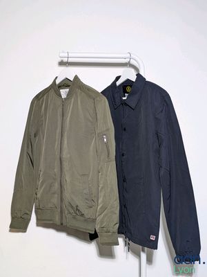 two jackets hanging on a clothes rack in a white room