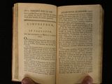 someone is holding an open book in their hands on a black surface