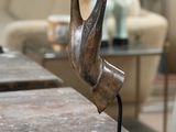 une sculpture en bronze représentant un oiseau posée sur une table en marbre