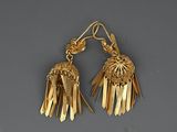pair of gold tone earrings with fringes on a grey background