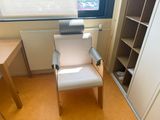 a white chair sitting in front of a window next to a desk