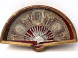 a gold and red fan on a white surface