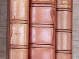 quatre livres sur une étagère, avec une horloge en arrière-plan
