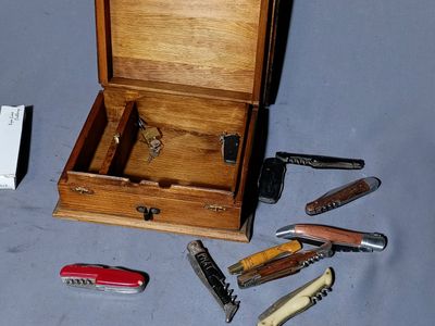 a small wooden box with several different types of knives in it