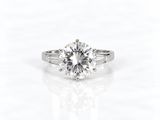 une bague de fiançailles en or blanc sertie d'un diamant rond taille brillant entouré de diamants taille baguette