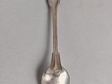 a silver spoon with a heart on it on a white surface
