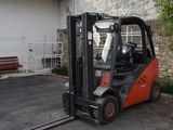 un chariot élévateur garé sur un parking à côté d'un bâtiment