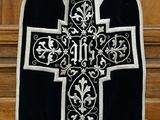 un gilet noir et blanc orné d'une croix, suspendu à une porte en bois