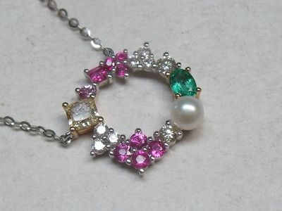 un collier composé de perles blanches, roses et vertes posé sur une table