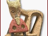 une sculpture représentant un chat tenant un champignon dans la gueule