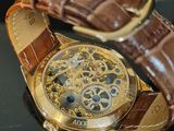a gold watch with a brown leather strap on a table