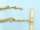 two pieces of gold chain with a long tassel on a blue background